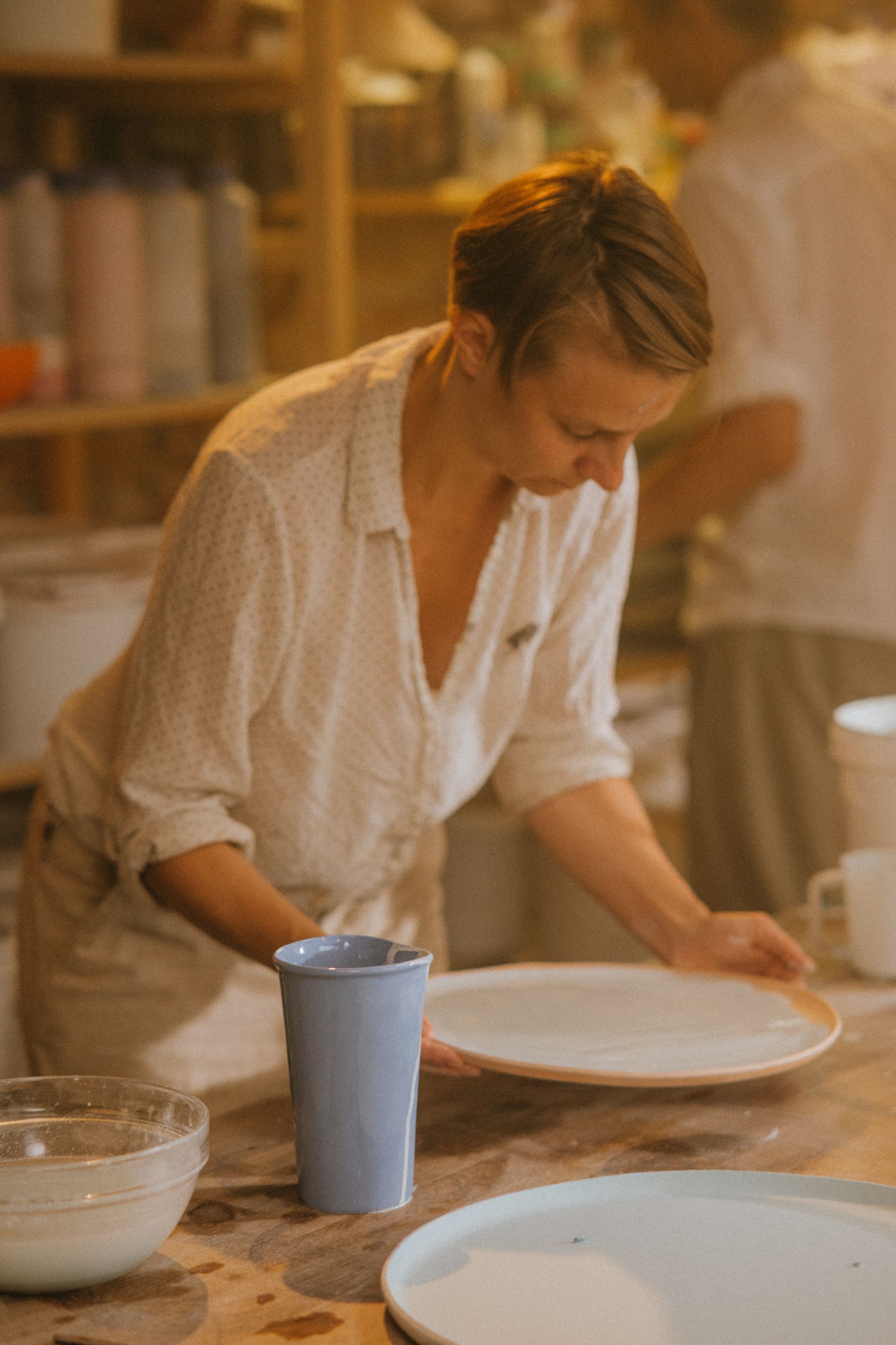 En keramisk kunstner arbejder på en tallerken i sit atelier
