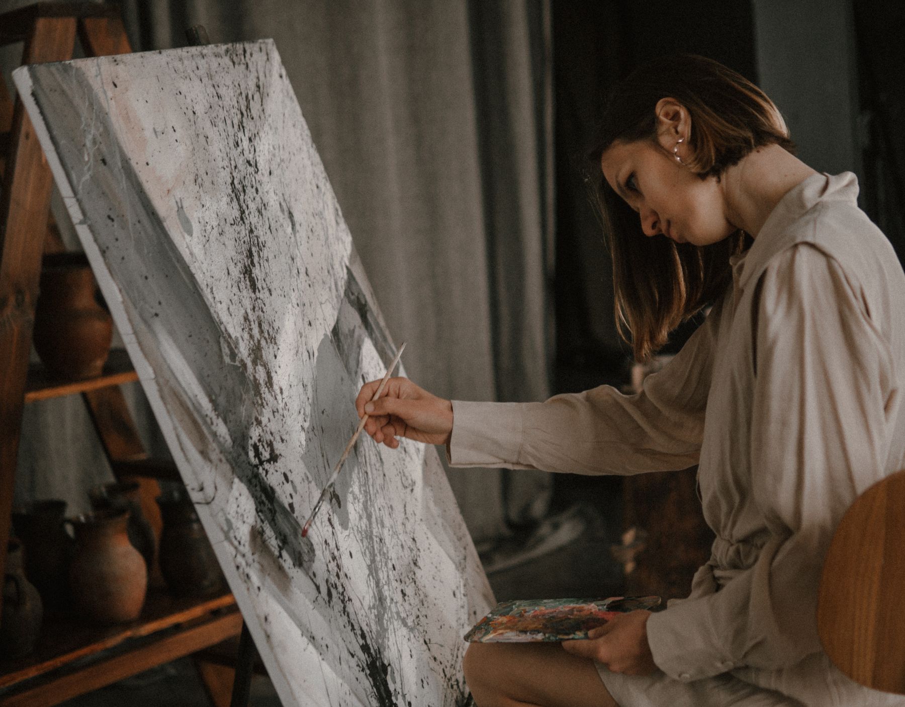 En kunstner maler på et stort lærred i sit atelier