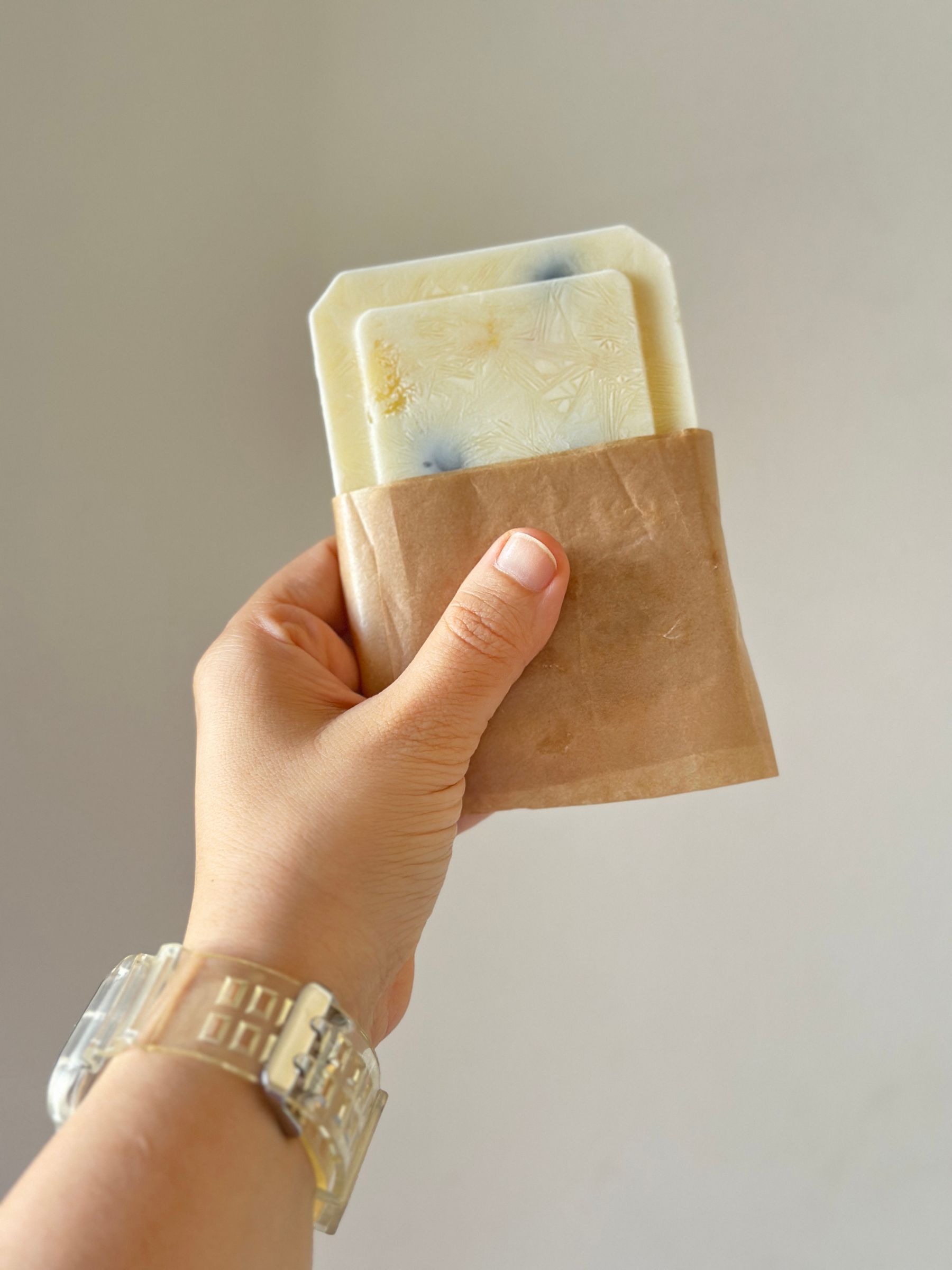 Main tenant un pain de savon dans un emballage en papier