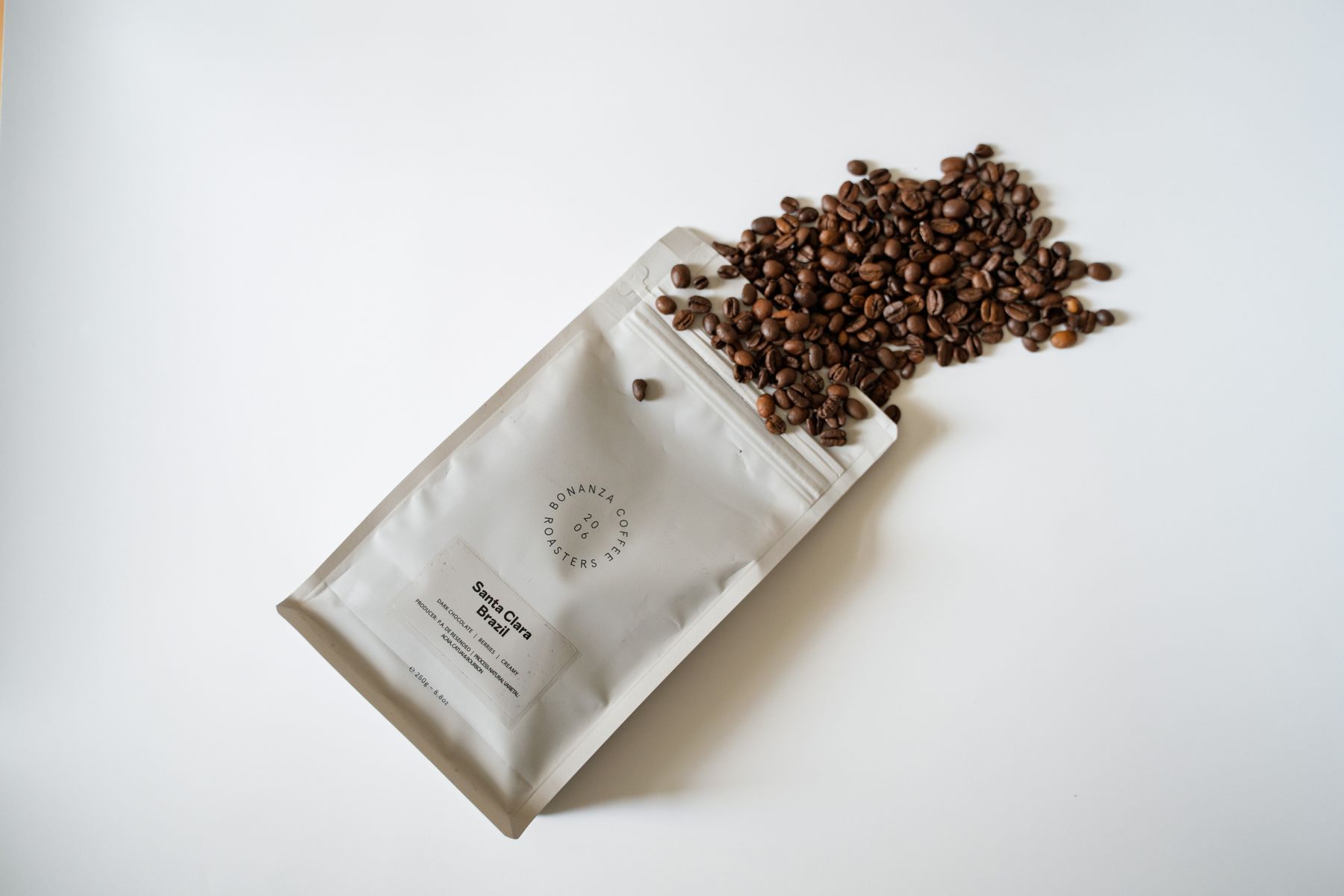 Un sachet de café blanc avec des grains de café torréfiés