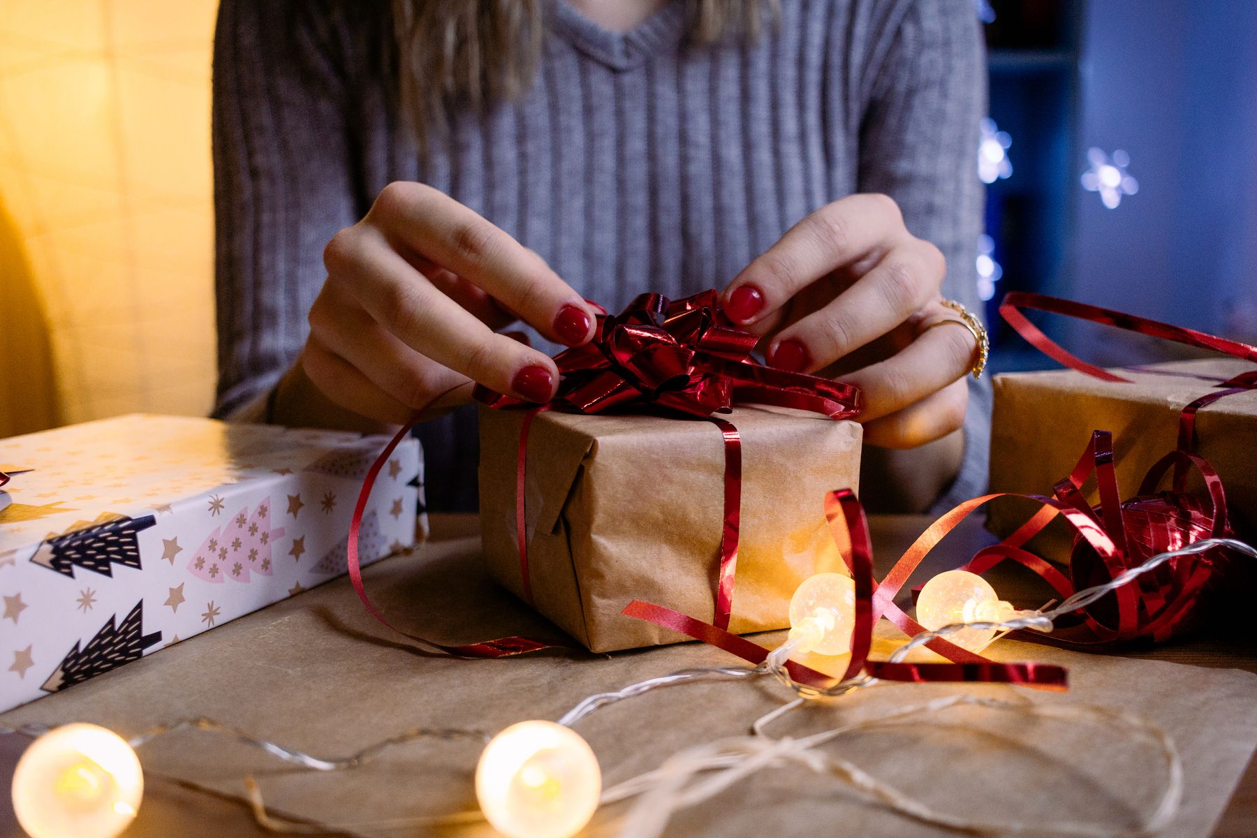 Mains emballant un cadeau avec un ruban rouge