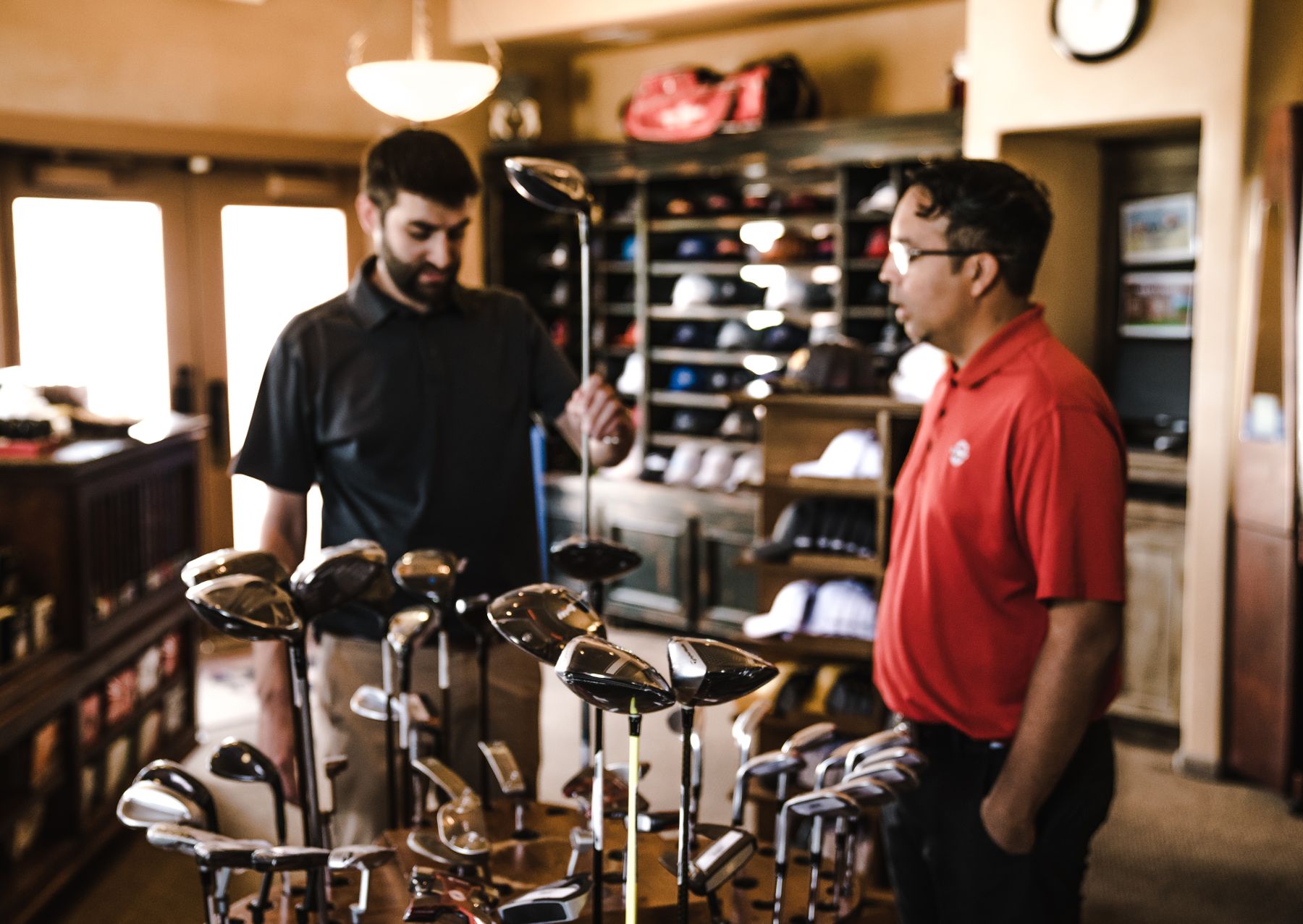 Ein Mitarbeiter und ein Kunde betrachten Golfschläger in einem Sportgeschäft