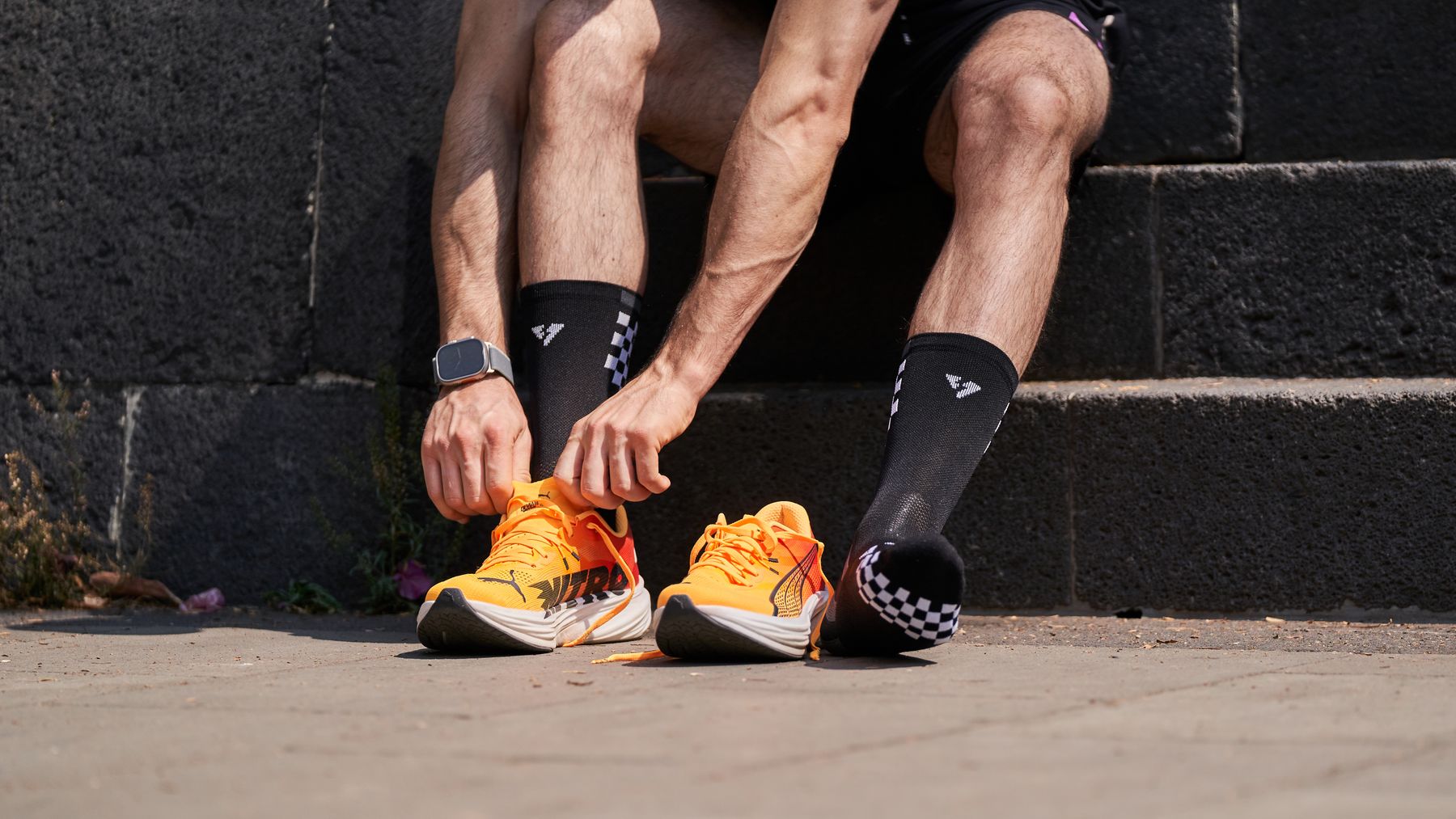 Ein Läufer bindet orange Schuhe auf einer Außentreppe