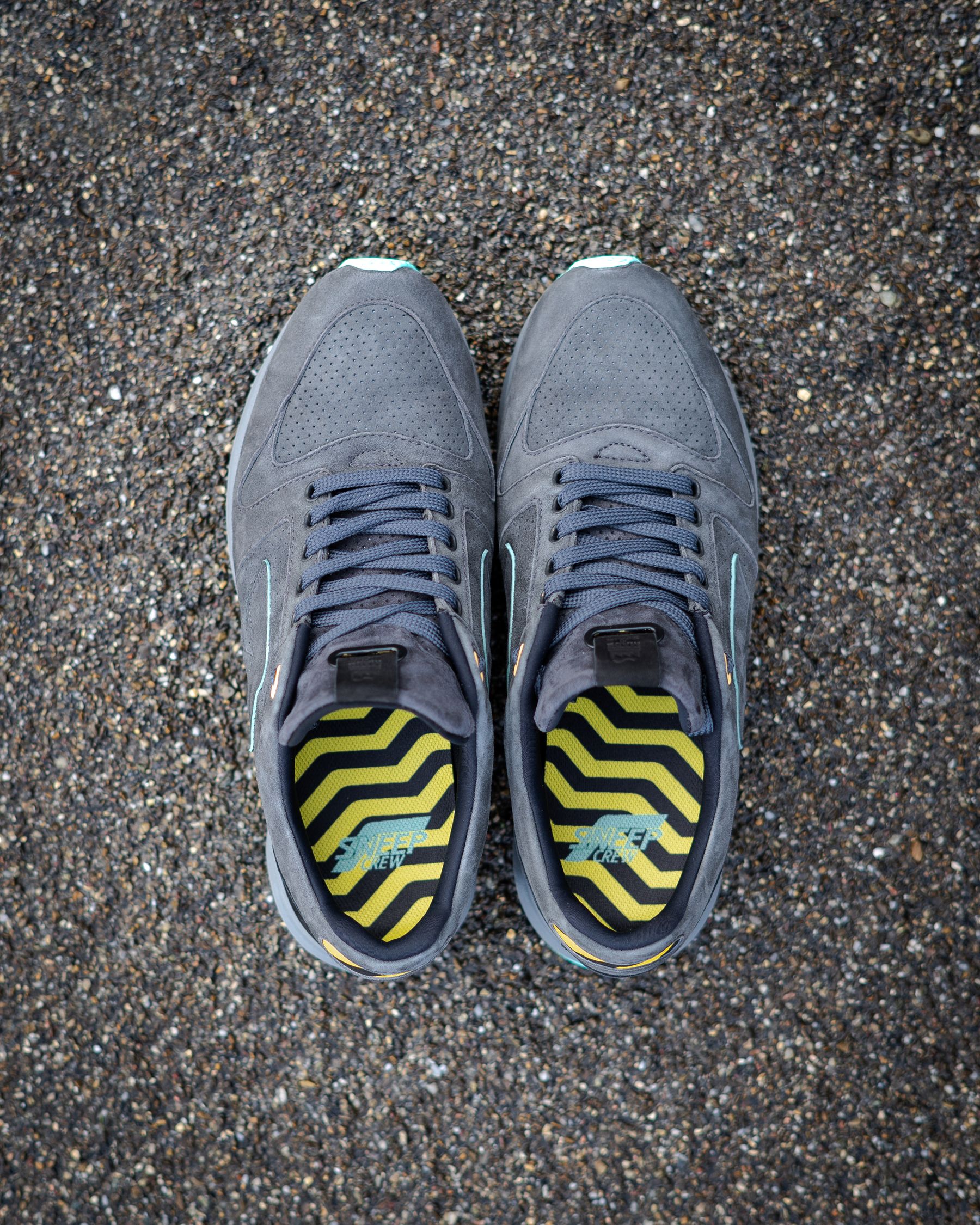 Graue Sportschuhe von oben auf einem Kiesweg